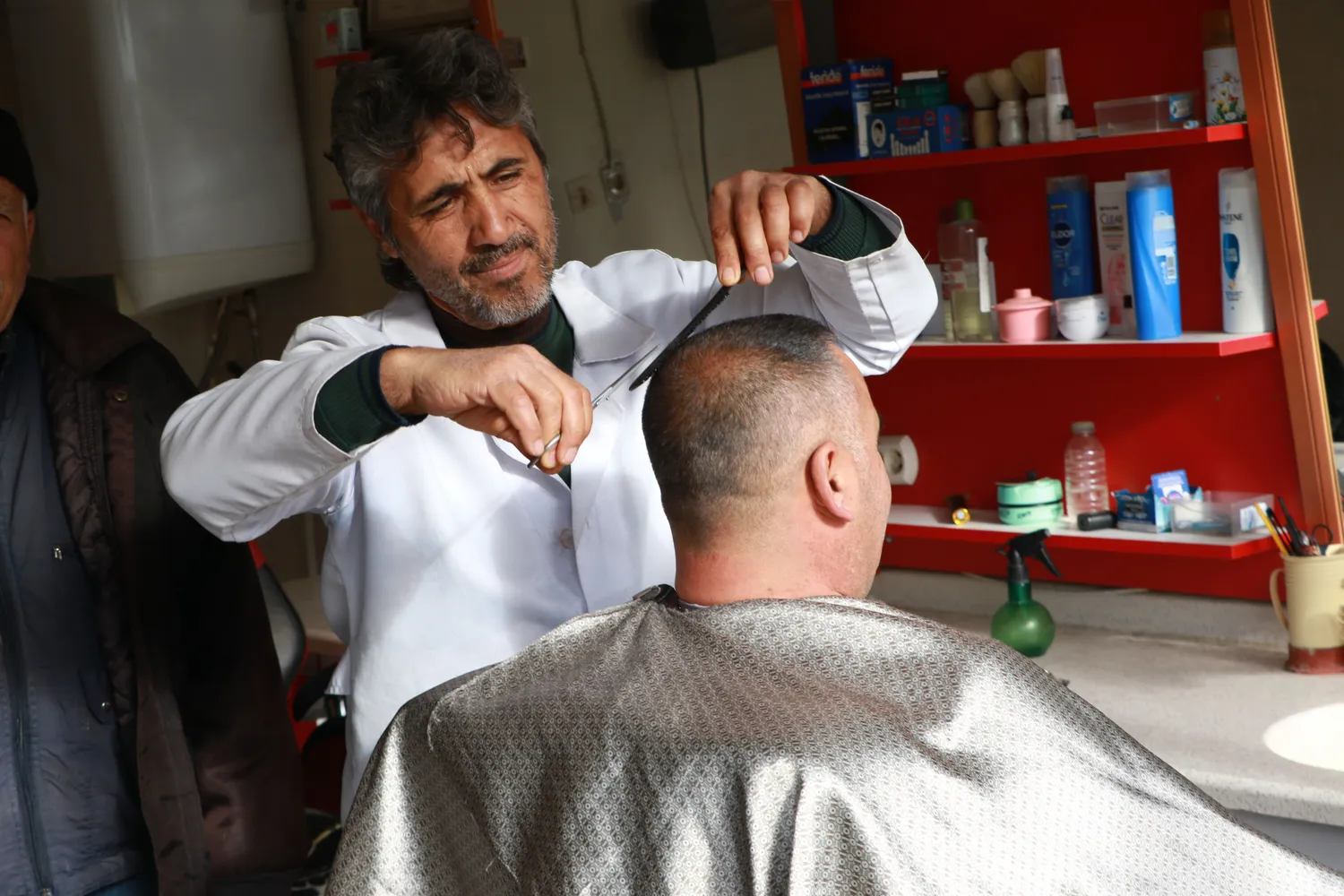 Barbier schneidet mit Schere und Kamm die Haare eines Kunden